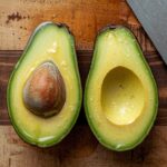 A close-up of a halved avocado, one half submerged in