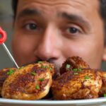 A close-up of a plate with crispy chicken thighs, a