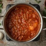 A large pot of rich, simmering Bolognese sauce on a
