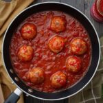 A sizzling skillet filled with meatballs simmering in a rich