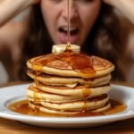 A stack of pancakes with syrup, some stuck together, on