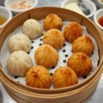 A vibrant dim sum spread on a bamboo steamer, featuring